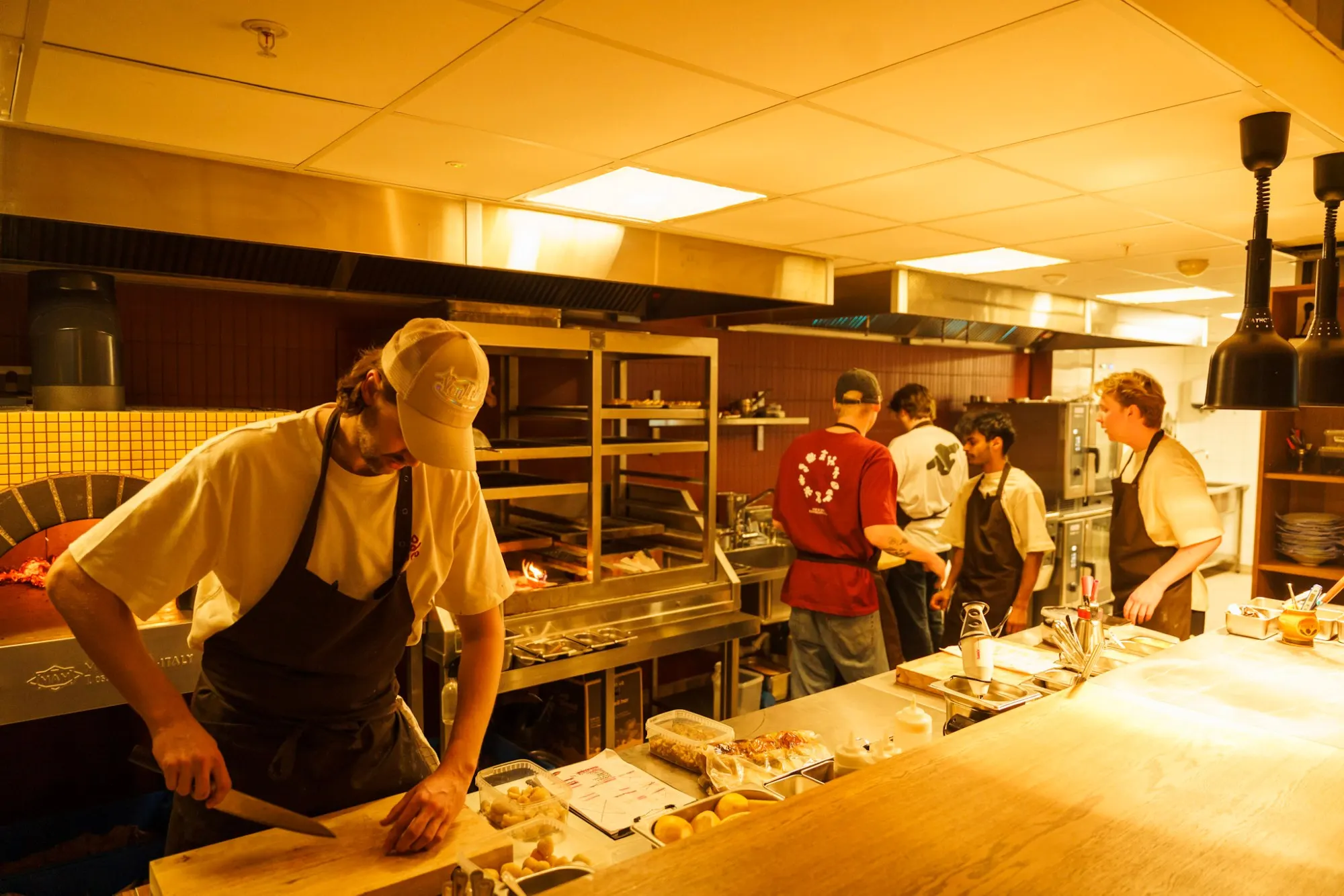 Kokker i arbeid på Rodeos åpne kjøkken, ved den vedfyrte ovnen og grillen
